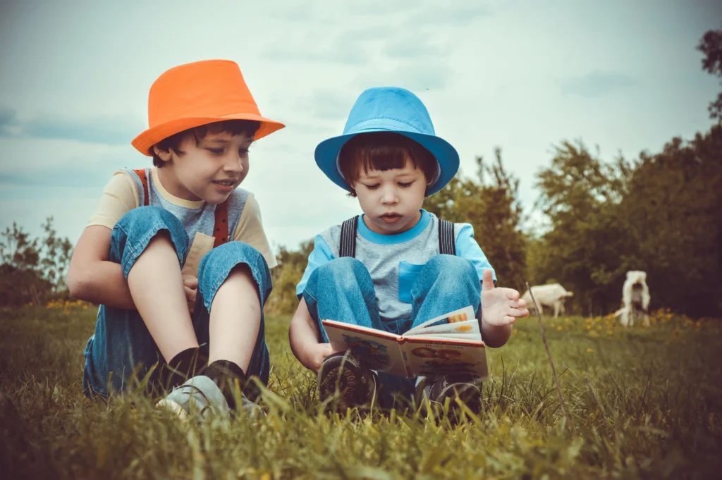 Children reading a book outdoors.